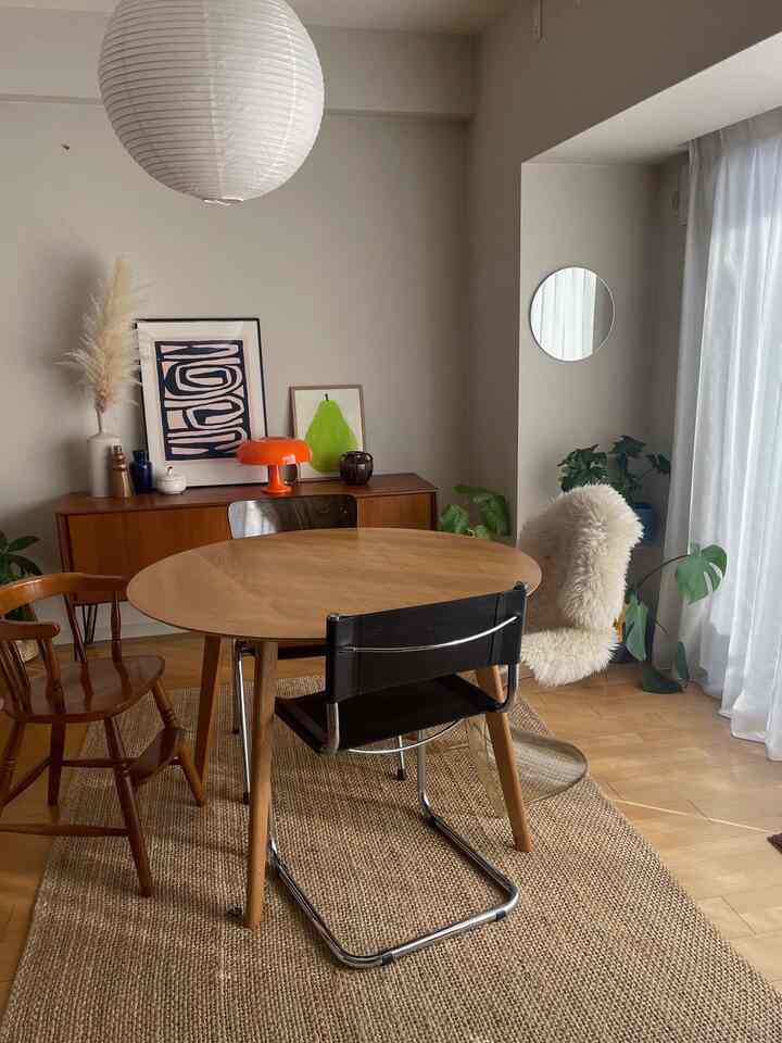 ベージュと木目調が調和したダイニング、ラウンドテーブルと多様な椅子が配置された自然で落ち着いた雰囲気のインテリア