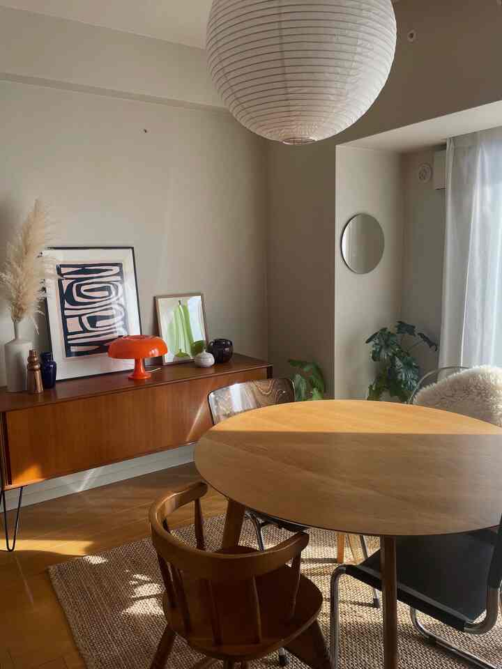 ナチュラルなブラウンのダイニングルーム、丸いダイニングテーブルと椅子、オレンジのテーブルランプが配置された雰囲気のあるインテリア