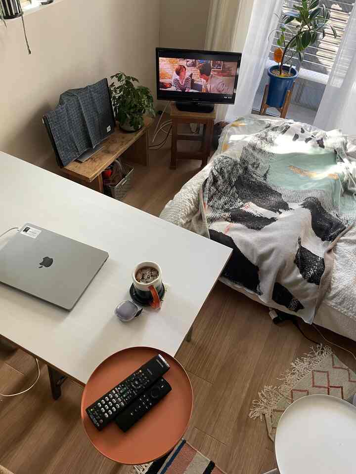 ナチュラル色調のワンルーム寝室とデスクが配置された居心地の良い一人暮らし空間