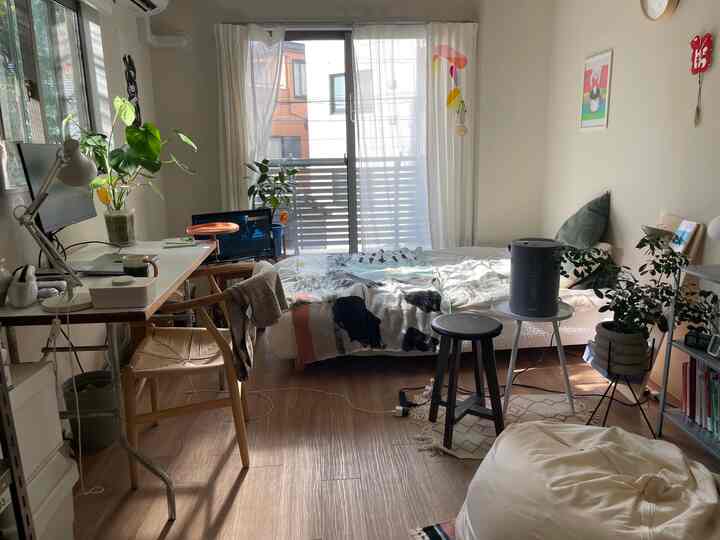 A natural and cozy studio apartment in white and brown tones featuring a bed and a work desk
