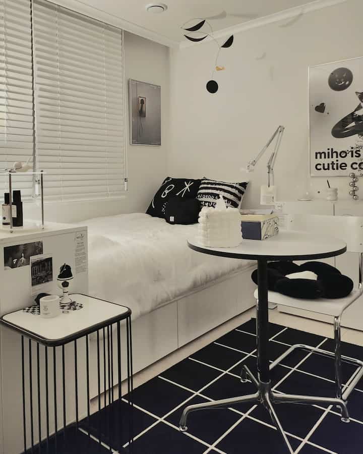 Small black and white toned studio bedroom featuring simple modern furniture and decor in a clean space