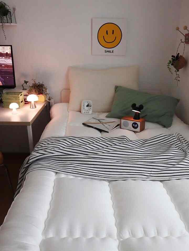 白とミント色調の子供部屋、ベッドとトッパーに暖かな照明とスマイル額縁が配置された雰囲気のあるインテリア