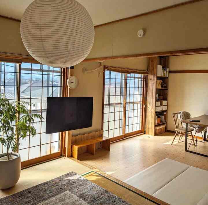 ナチュラルな木目調の和モダン6畳リビング、大型の丸型照明とデスク、植物が配置された雰囲気のある空間