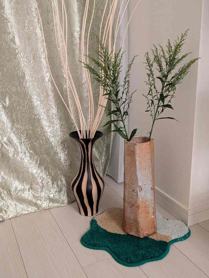 緑の植物と自然素材の質感の花瓶が配置されたナチュラルな色調の室内のコーナー