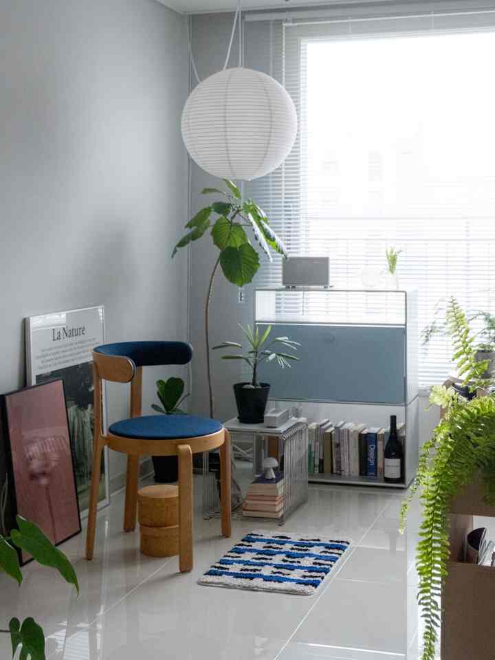 ブルーとシルバーのトーンが調和したリビングのコーナー、ヴィンテージチェアと棚、緑の植物が配置された雰囲気のある空間