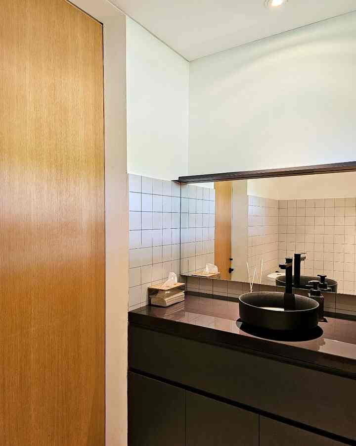 White and wood-toned powder room featuring a black sink and cabinetry, creating a sleek modern atmosphere