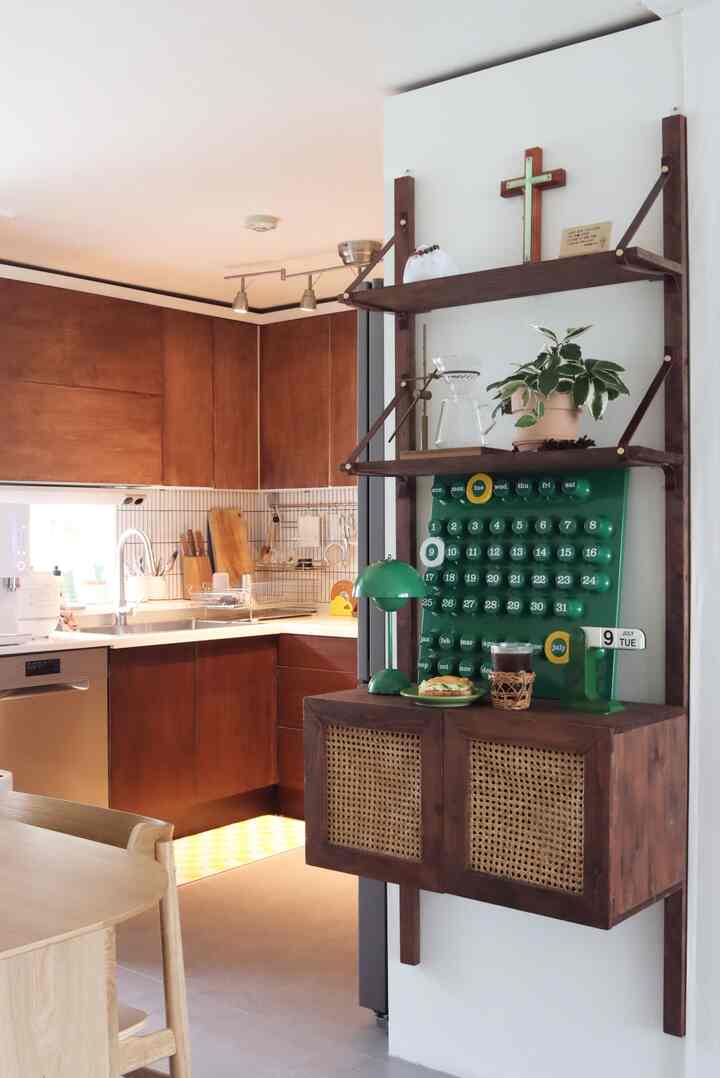 Cozy apartment kitchen featuring warm wood tones and green accents, with wall shelves and home cafe accessories arranged neatly
