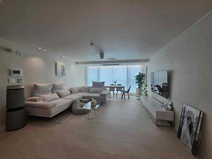 ホワイトとウッドトーンが調和した30坪クラスのアパートリビング、大型コーナーソファとシーリングファンが配置された清潔でモダンな空間