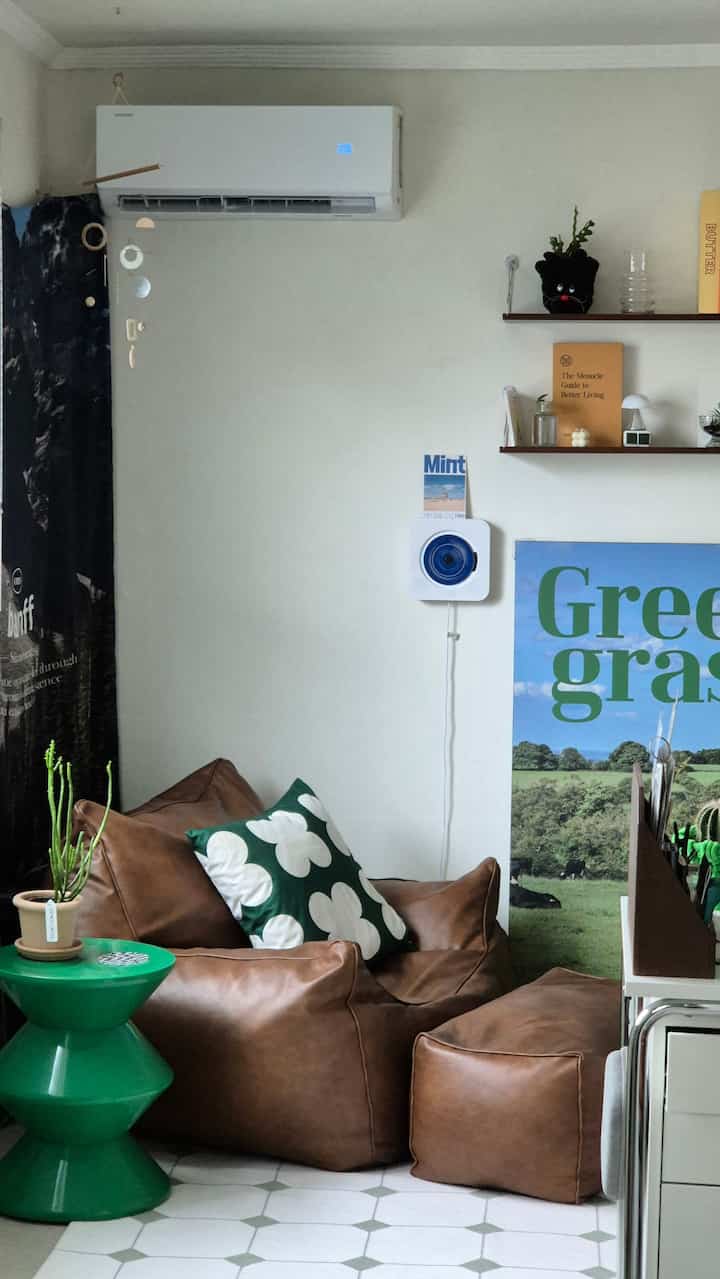 ホワイトの壁にブラウンのビーズクッションソファとグリーンのサイドテーブルが配置された落ち着いた雰囲気のリビング