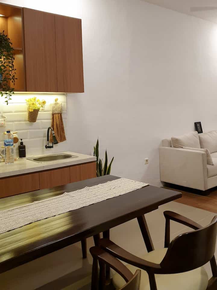 Natural modern toned kitchen and dining room featuring wooden dining table and simple sofa with cozy atmosphere