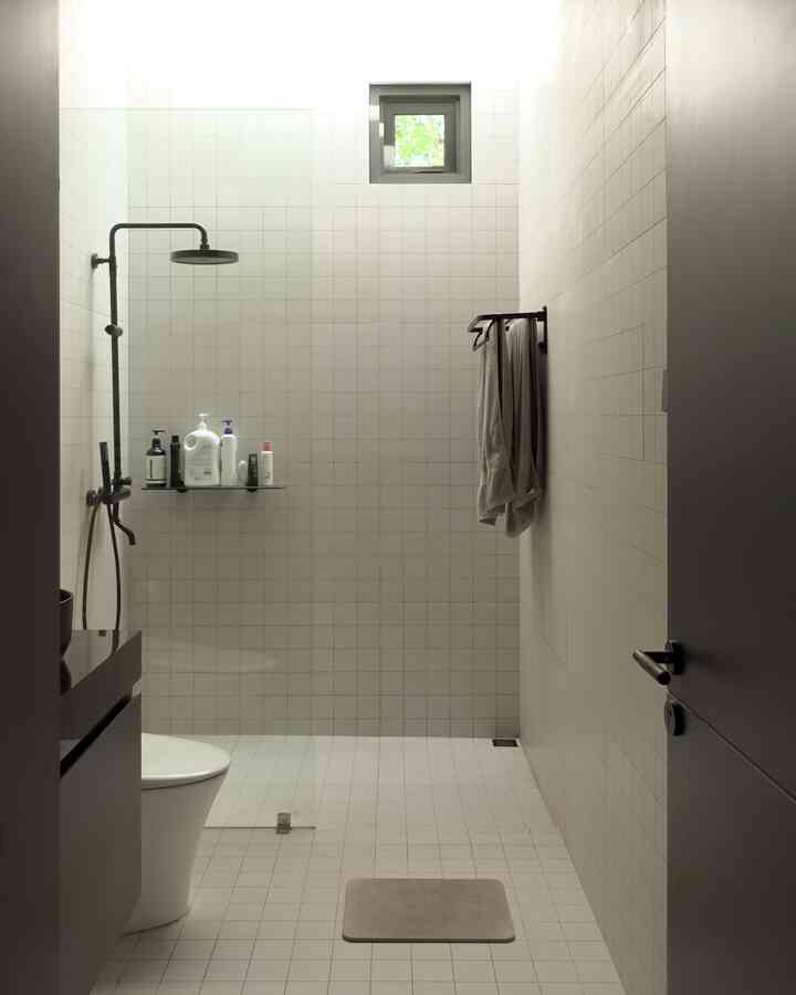 Modern bathroom with white tiled walls and floor, featuring shower area, sink, and toilet in a clean layout