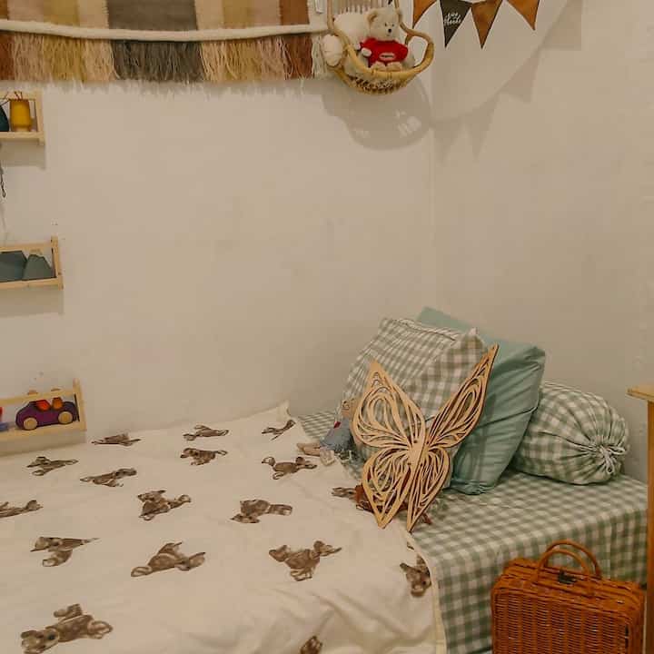 Natural color and wood tone kids' bedroom with boho style décor featuring toys and soft blankets for a cozy atmosphere