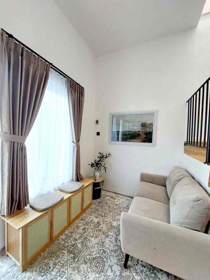 Beige and wood tone small living room featuring a beige sofa and wooden shoe cabinet with seating by the window, creating a cozy atmosphere
