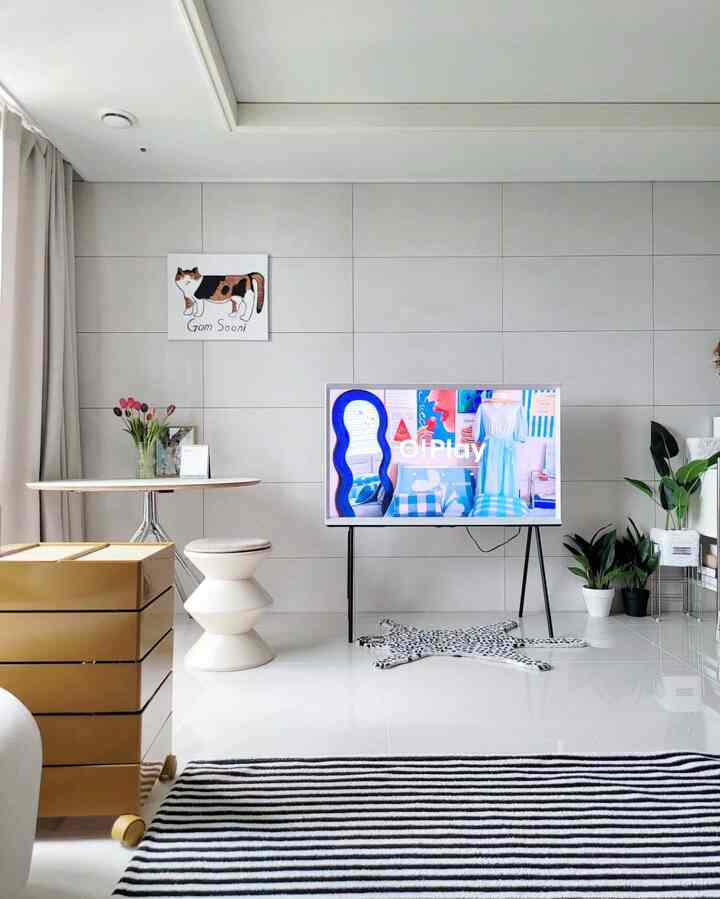 White tone living room featuring TV, cat illustration, multiple rugs, and plants in a modern clean space