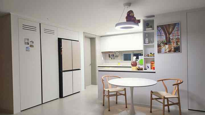 白と木目調の調和したキッチンタイプ、円形テーブルとラタンチェアが配置されたシンプルで雰囲気あるインテリア