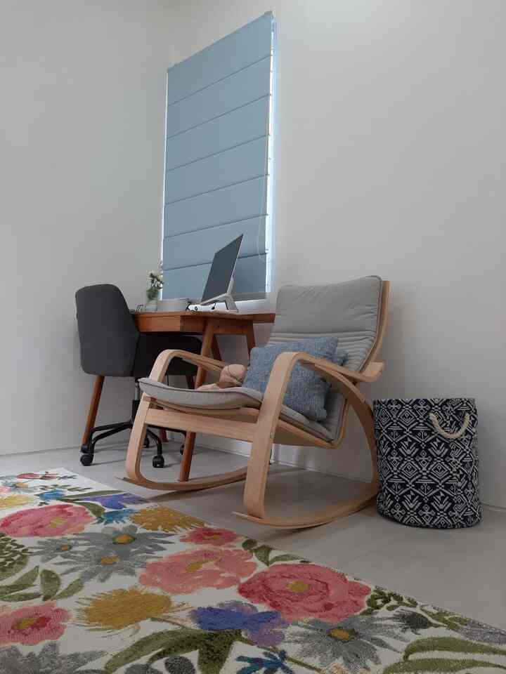 Pastel blue blinds and natural wood armchair in a simple, cozy home office space