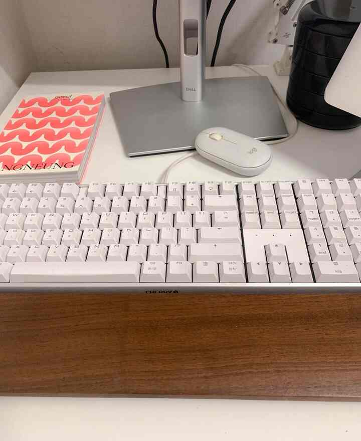 白と茶色のトーンの机の上に、キーボードとマウスが配置された清潔感のあるホームオフィスのインテリア