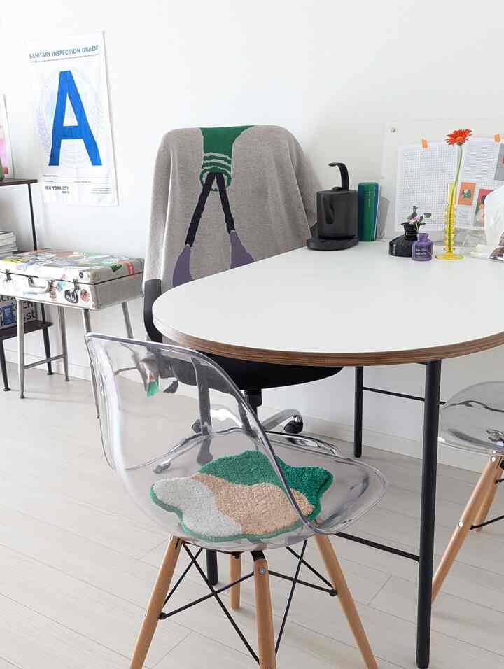 白と黒のトーンでまとめられたダイニングルーム、透明なチェアとシンプルなテーブルが配置されたすっきりとしたホームオフィス空間