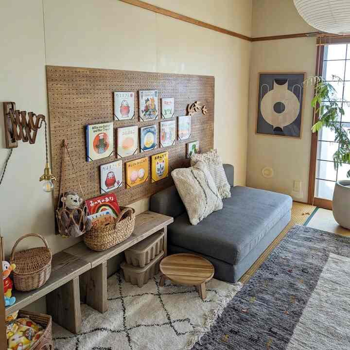 ナチュラルな色調の4人暮らし用リビング、子供向け絵本ディスプレイとソファが配置された落ち着いた畳の部屋