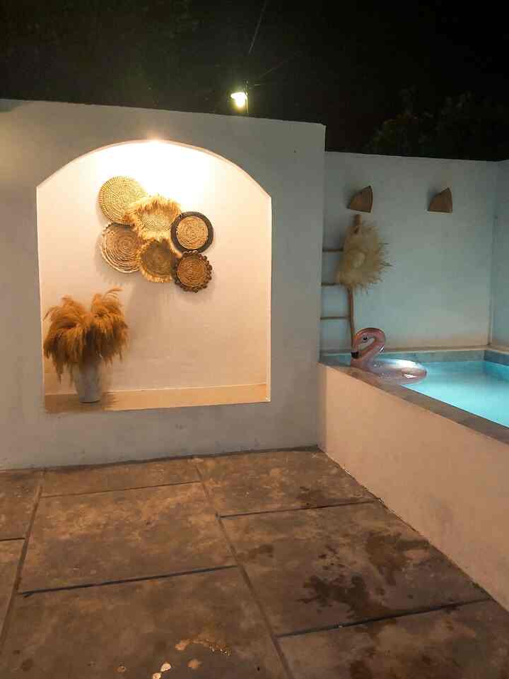 Mediterranean-style balcony with white walls and natural-toned decor, featuring a mini plunge pool, vase, and ambient lighting in a cozy outdoor setting