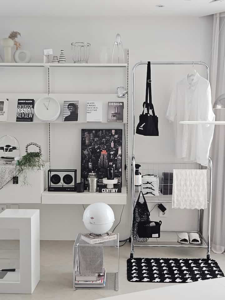ホワイトとシルバーのモダンな空間、棚やメタルの洋服掛け、ミニマルな小物が配置された清潔感のあるインテリア。