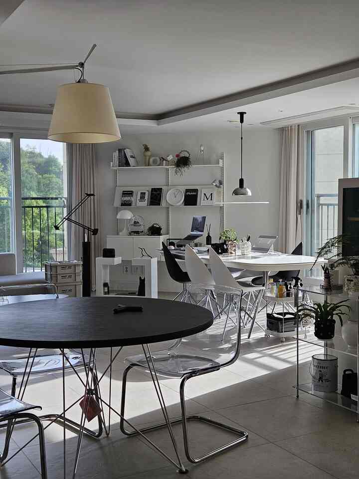 白と黒のモダンなリビング、壁棚と透明な椅子、ダイニングテーブルが配置された清潔で明るいインテリア