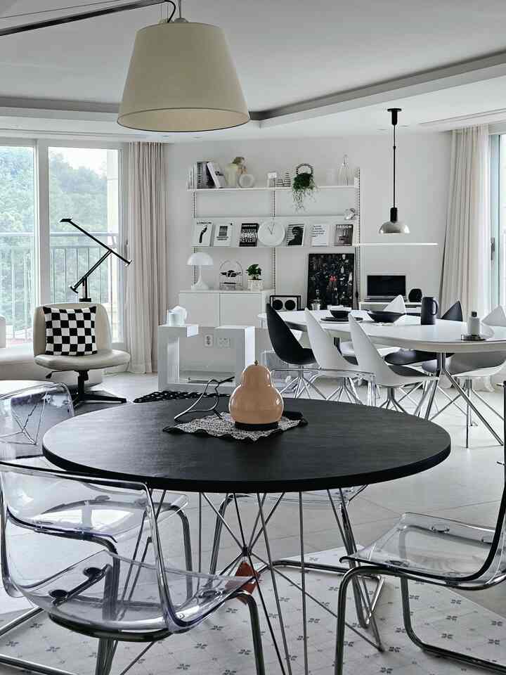 白と黒のモノトーンが特徴的なダイニングルーム、透明な椅子と丸いダイニングテーブルが配置されたモダンで洗練されたインテリア