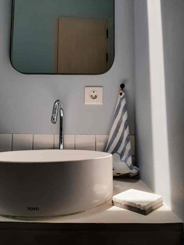 Gray-toned bathroom featuring a white washbasin, mirror, and towel with a clean, minimalist atmosphere
