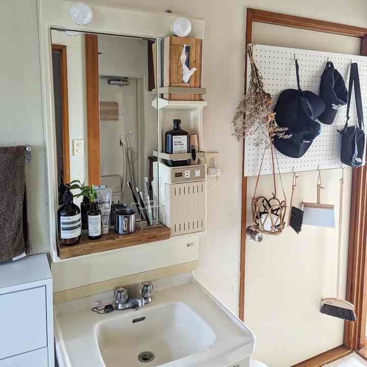 ホワイトと木目調のバスルーム、洗面台とタオル、多様なバスルームアイテムが配置された清潔感ある空間