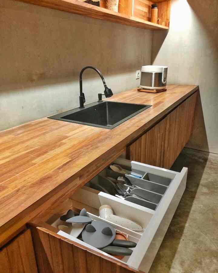 Compact kitchen space featuring warm wood tones and black sink, showcasing neat modern storage ideas and sleek design