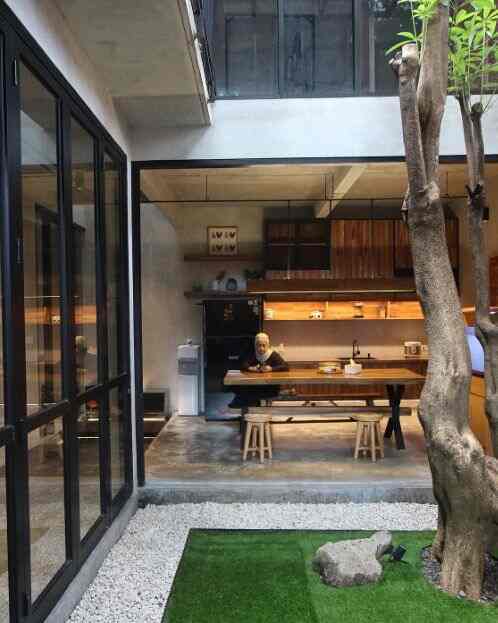 Natural wood tones and concrete floor in a modern kitchen space featuring wooden dining table and stools in a cozy studio apartment