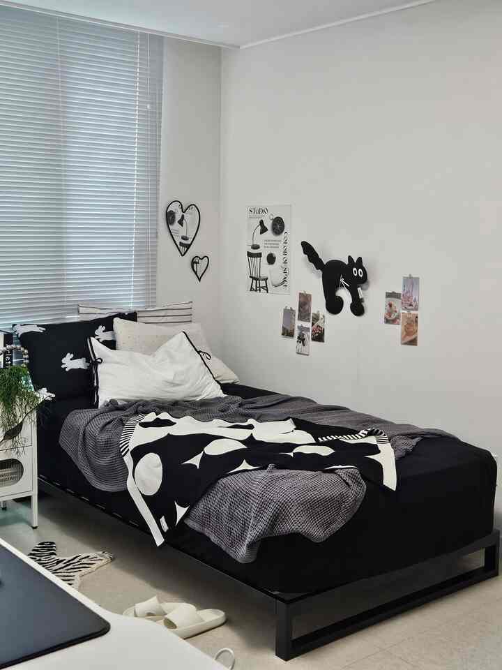 Monotone black and white kids' bedroom featuring a metal bed frame with cushions and blankets, creating a clean modern atmosphere