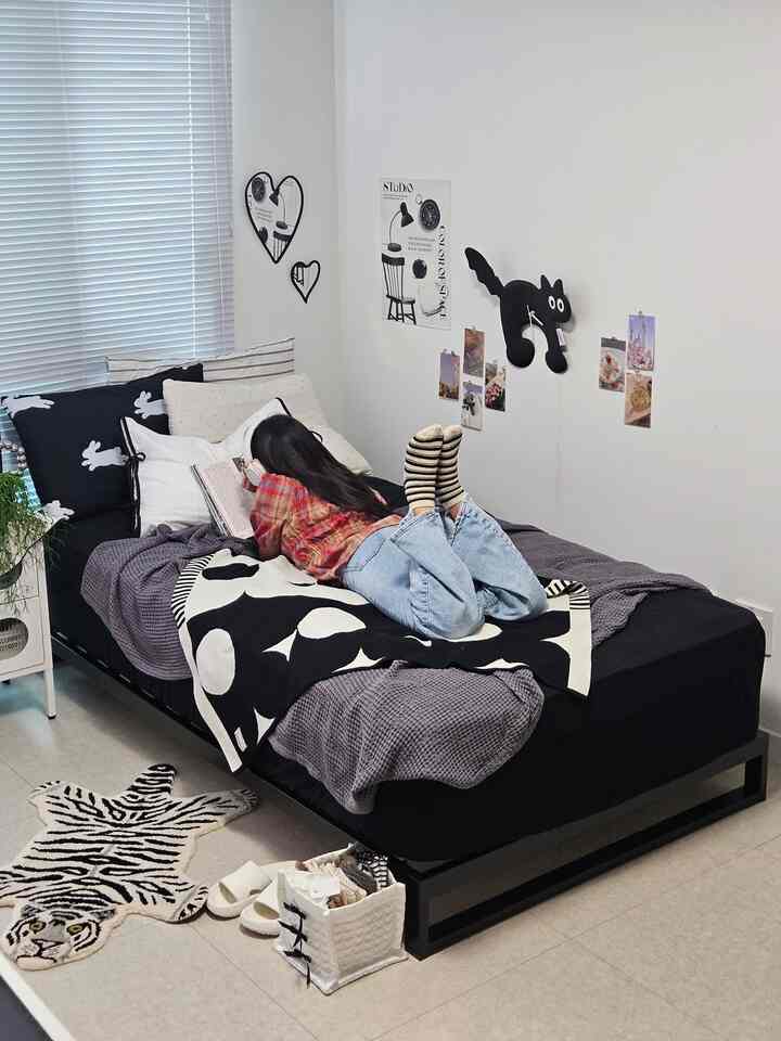 A black bed with blankets in a white-walled bedroom designed for a single household