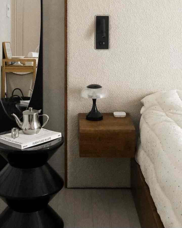 Wood tone, black, and white bedroom featuring black table, wooden nightstand in mid-century modern style