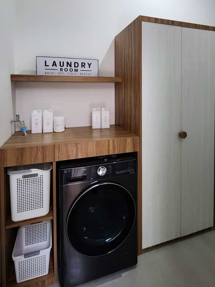 Wood tone cabinetry with a black washing machine in a clean, minimalist laundry room space