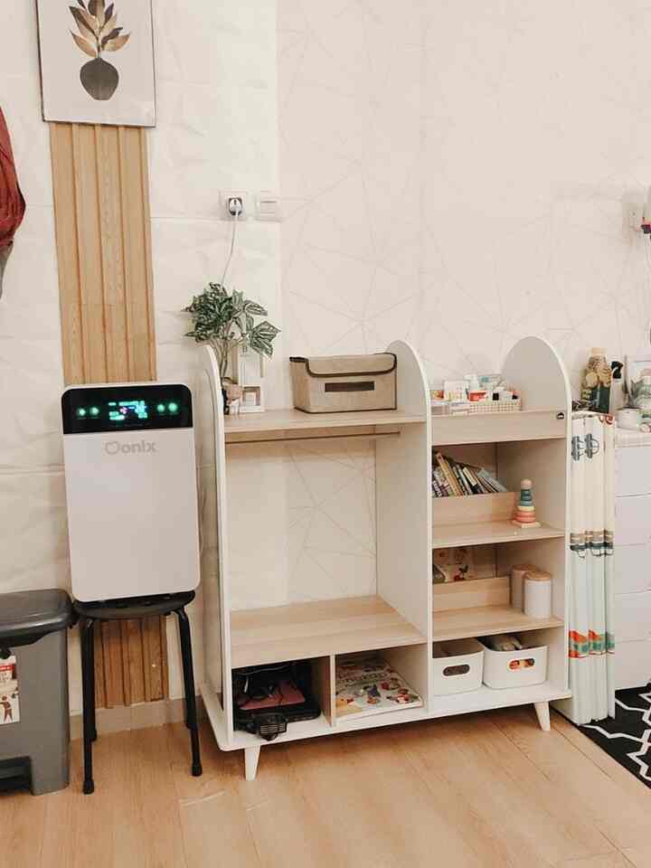 Kids' room storage area with natural wood flooring and white shelving against a geometric patterned wall
