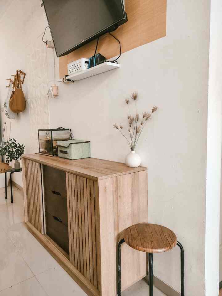 Natural wood-toned living room featuring a TV wall with storage cabinets and a cozy, practical Japandi-style setup