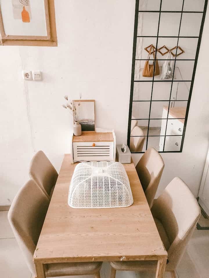 Natural wood tone dining room featuring a wooden table and fabric dining chairs with a simple aesthetic