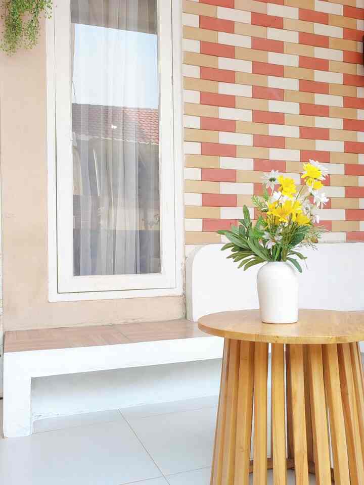 Beige and white toned veranda space featuring a round wooden table with a white vase filled with yellow flowers, clean interior