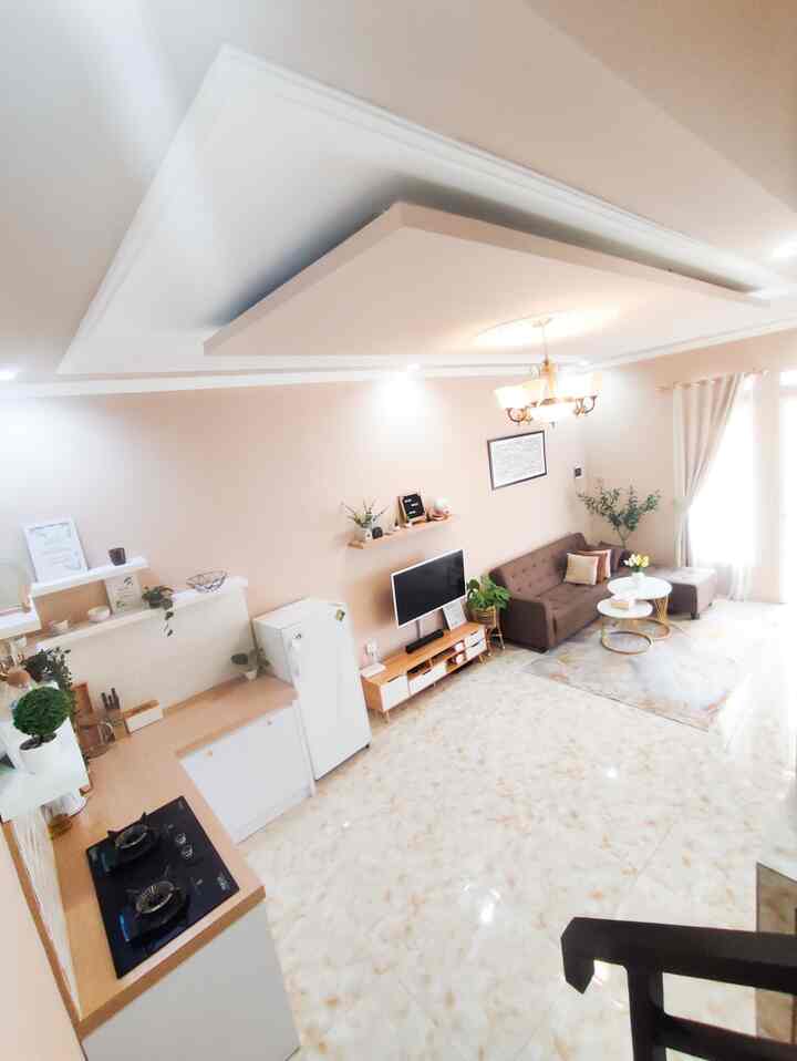 Natural-toned living room and kitchen featuring a brown sofa and white curtains with warm, cozy atmosphere