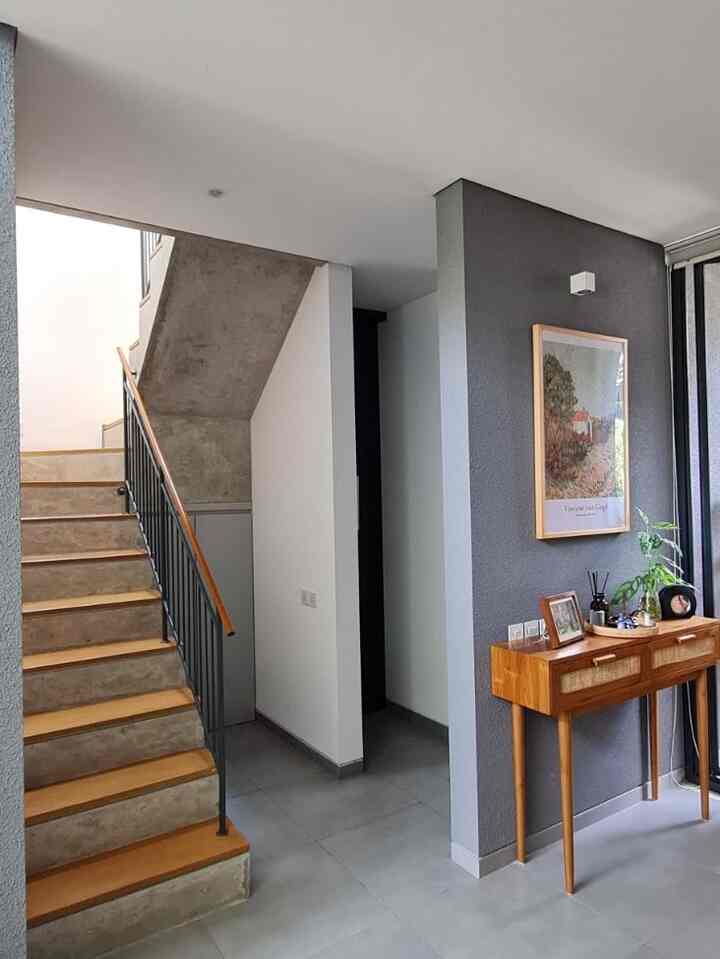Gray and white toned entrance space featuring stairs and a wooden console table with a clean modern interior