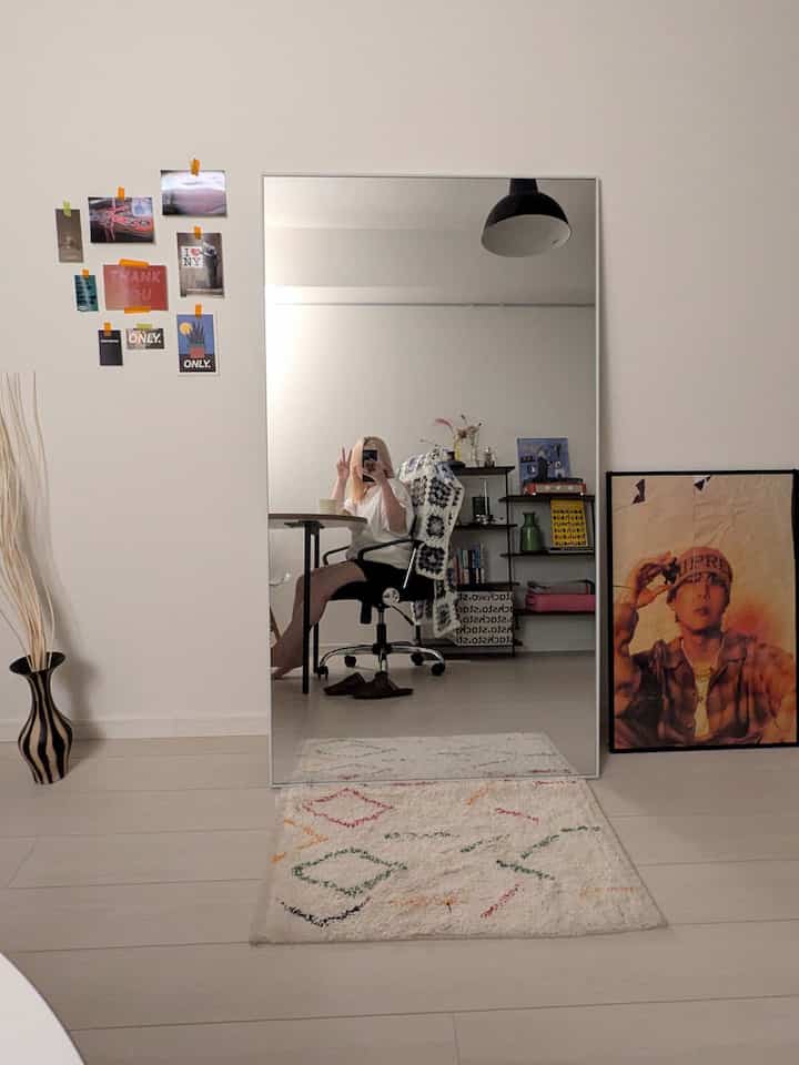 白を基調とした玄関スペース、印象的な大きな全身鏡とペンダントライトが配置されたミニマルなインテリア