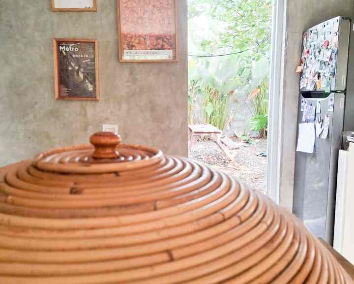 Natural toned kitchen and veranda space, featuring a rattan food cover and green plants creating a cozy atmosphere