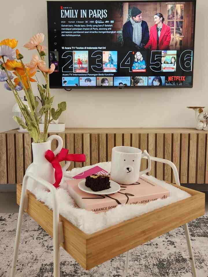 White and wood tone living room featuring a TV and a wooden tray with tableware creating a cozy ambiance