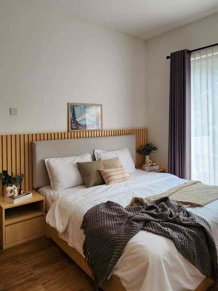 Natural wood tone and white bedroom featuring a comfortable bed with pillows and throws in a cozy setting