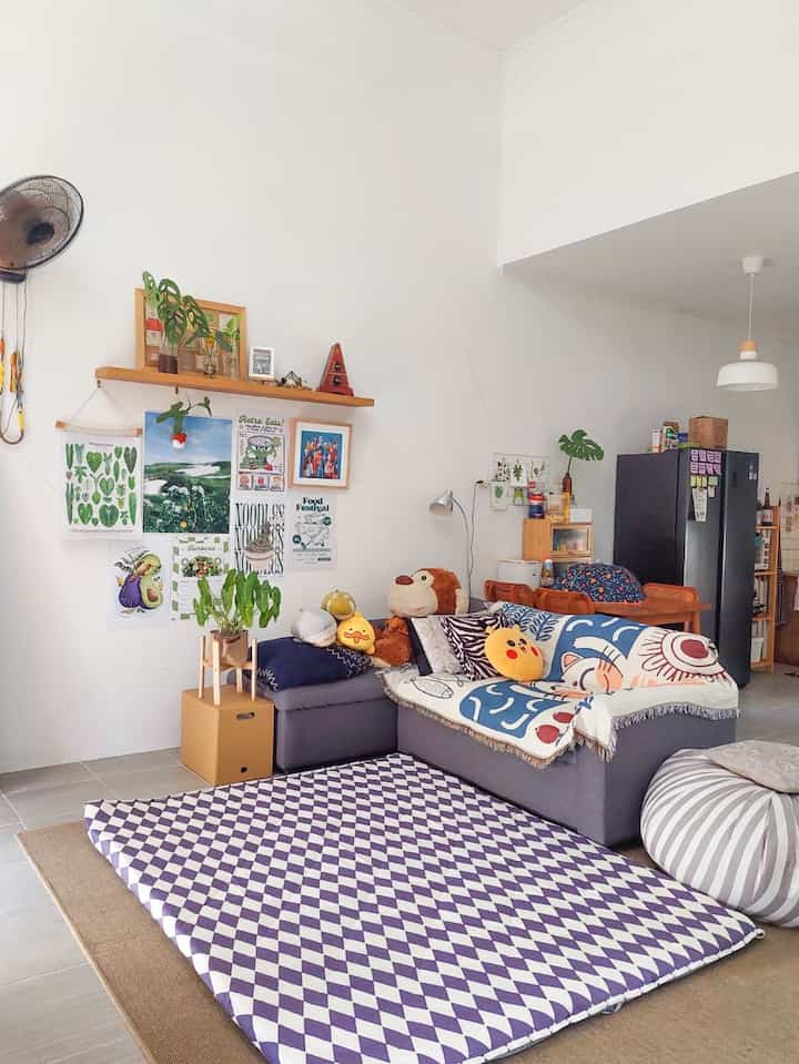 Natural-toned living room featuring a large gray sofa, colorful cushions, and patterned rug creating a cozy atmosphere