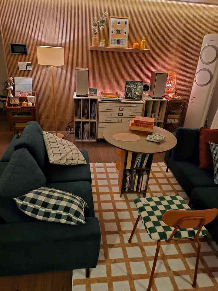 温かみのある木目調の壁と深緑のソファが配置された居心地の良いリビング