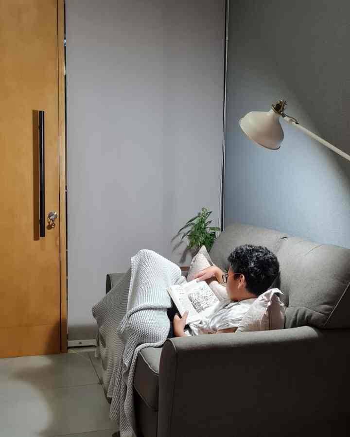 Charcoal sofa and white floor lamp in a simple modern living room, a cozy reading space