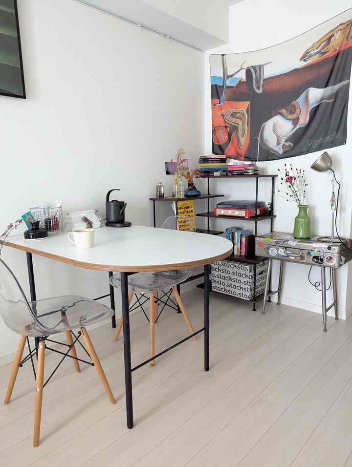 白を基調とした二人用ダイニングルーム、透明の椅子と洗練されたレイアウト、カフェ風のインテリアが印象的な空間