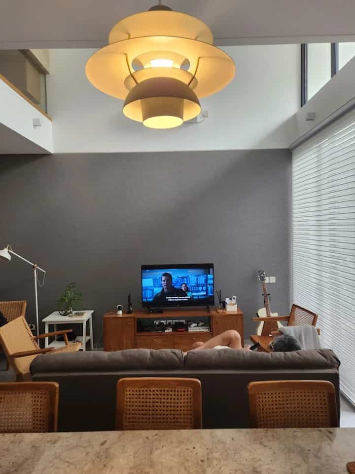 Modern living room with gray walls and wood-tone furniture, featuring a large pendant light centrally